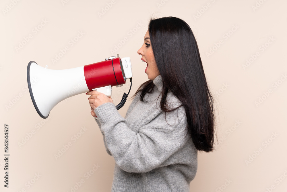 Naklejka premium Young Colombian girl over isolated background shouting through a megaphone