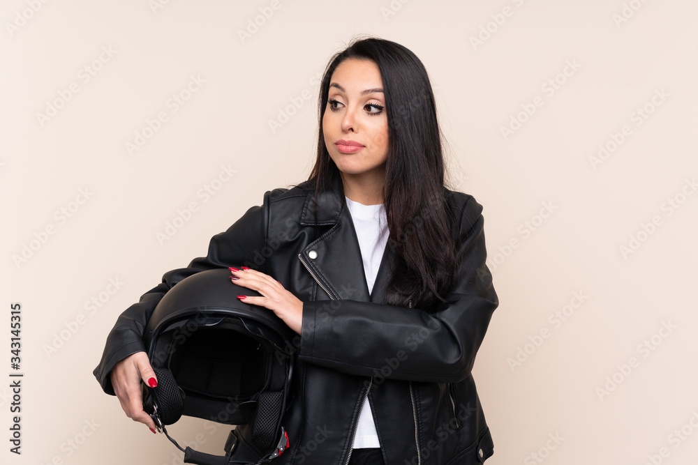 Young Colombian girl holding a motorcycle helmet over isolated background thinking an idea