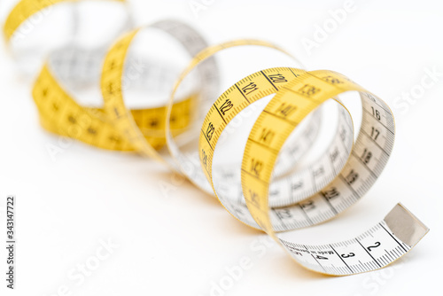 Yellow measuring tape on white background. Measurement of length and circumference. Lose weight and get fat.