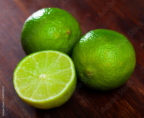 Cut fresh raw green limes on wooden table in home kitchen