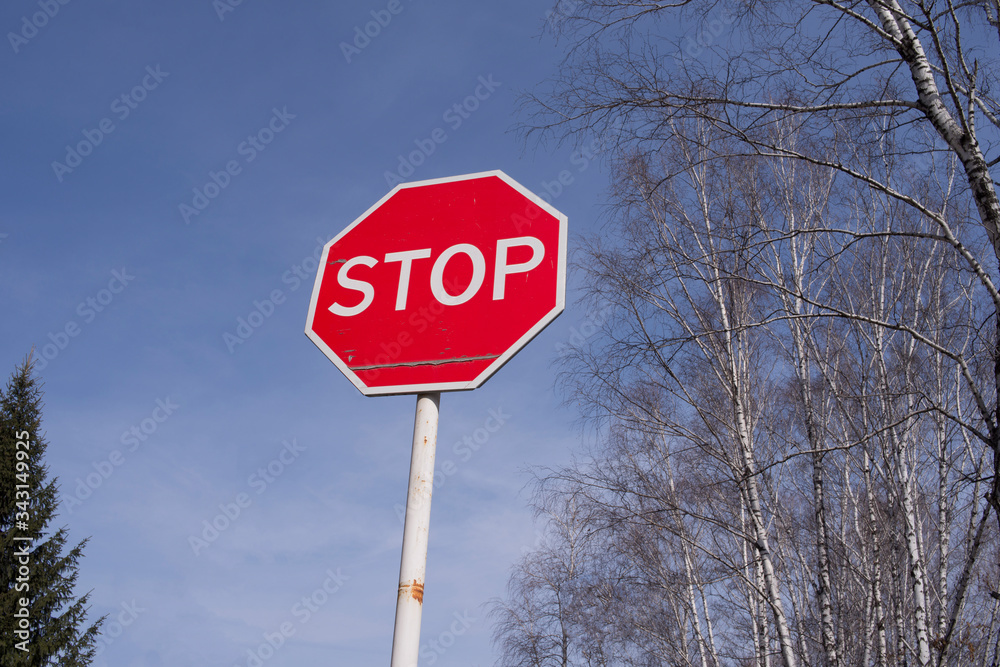 Stop sign against the sky and trees. Sign warning of the prohibition.