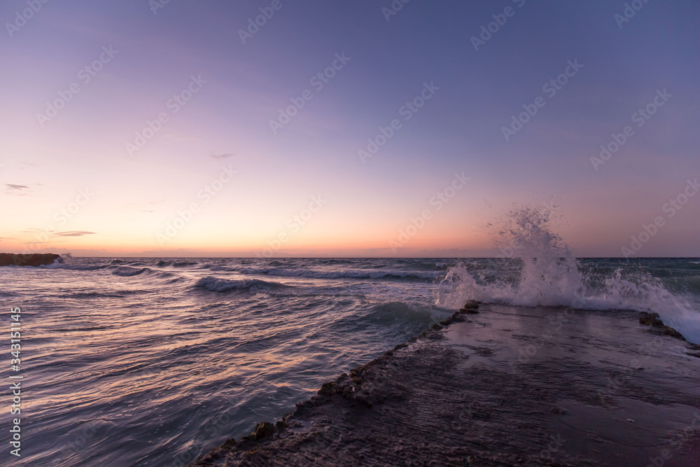 tropical beach and sea with waves and sunset reflections in the water