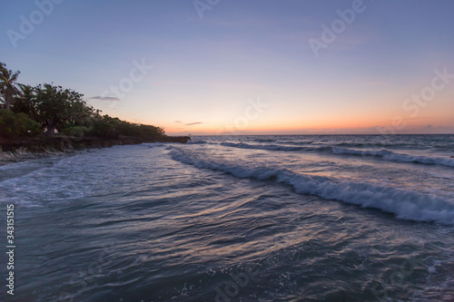 tropical beach and sea with waves and sunset reflections in the water