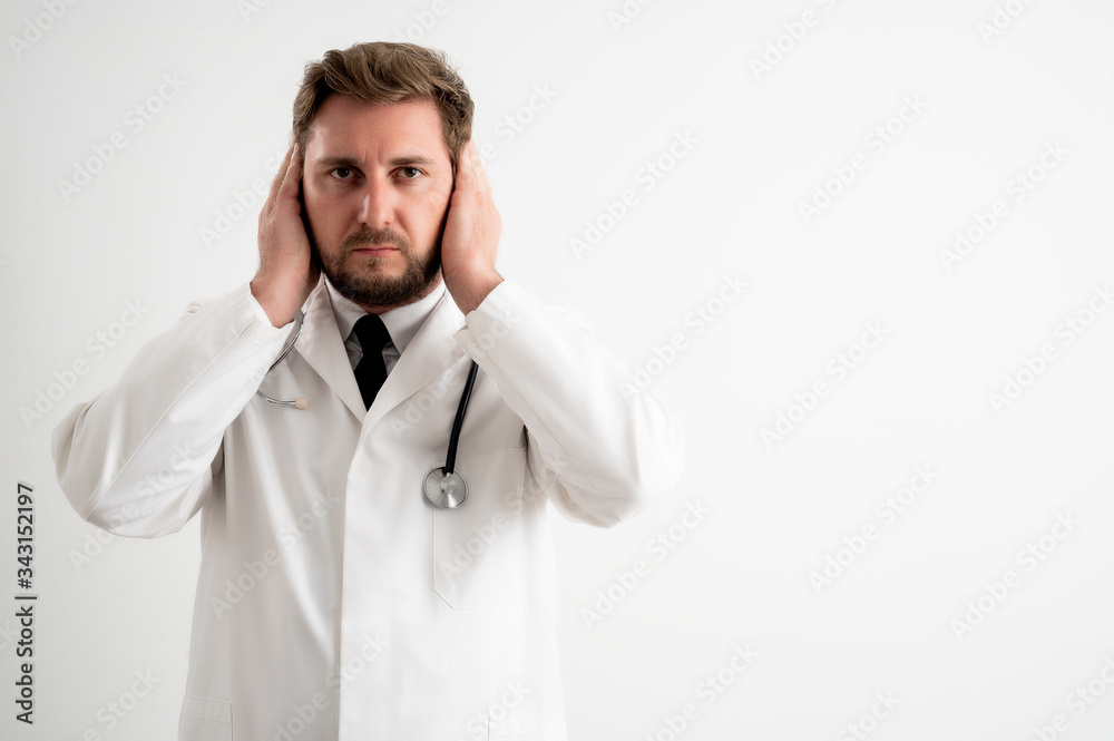 Male doctor with stethoscope in medical uniform covering ears like deaf concept Male doctor with stethoscope in medical uniform covering ears like deaf concept
