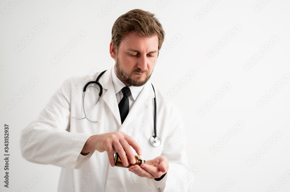 Male doctor with stethoscope in medical uniform spilling pills from bottle Male doctor with stethoscope in medical uniform spilling pills from bottle