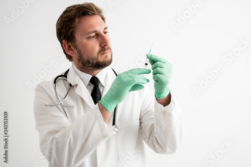 Male doctor with stethoscope in medical uniform with medical glove and syringe in hand photo