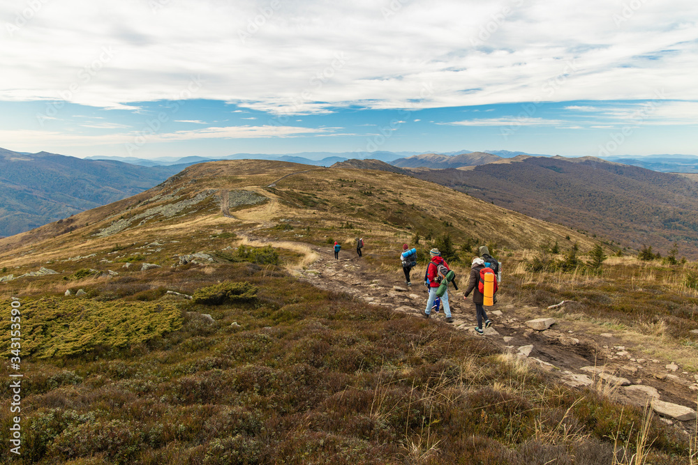 group of people back to camera walking on mountain ridge highland windy scenery environment moody nature surrounding of autumn weather