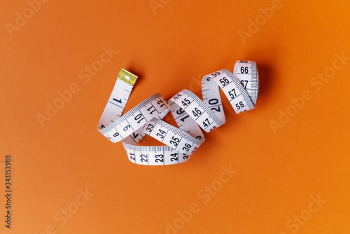 Orange background with centimeter. Diet and healthe care concept. Copy space. Place for text and design.