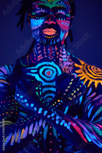 young handsome african man with fluorescent prints on body glowing on neon lights  colorful prints  body art concept