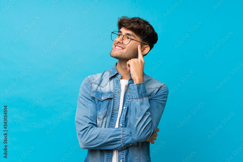 Young handsome man over isolated blue background with glasses Young handsome man over isolated blue background with glasses