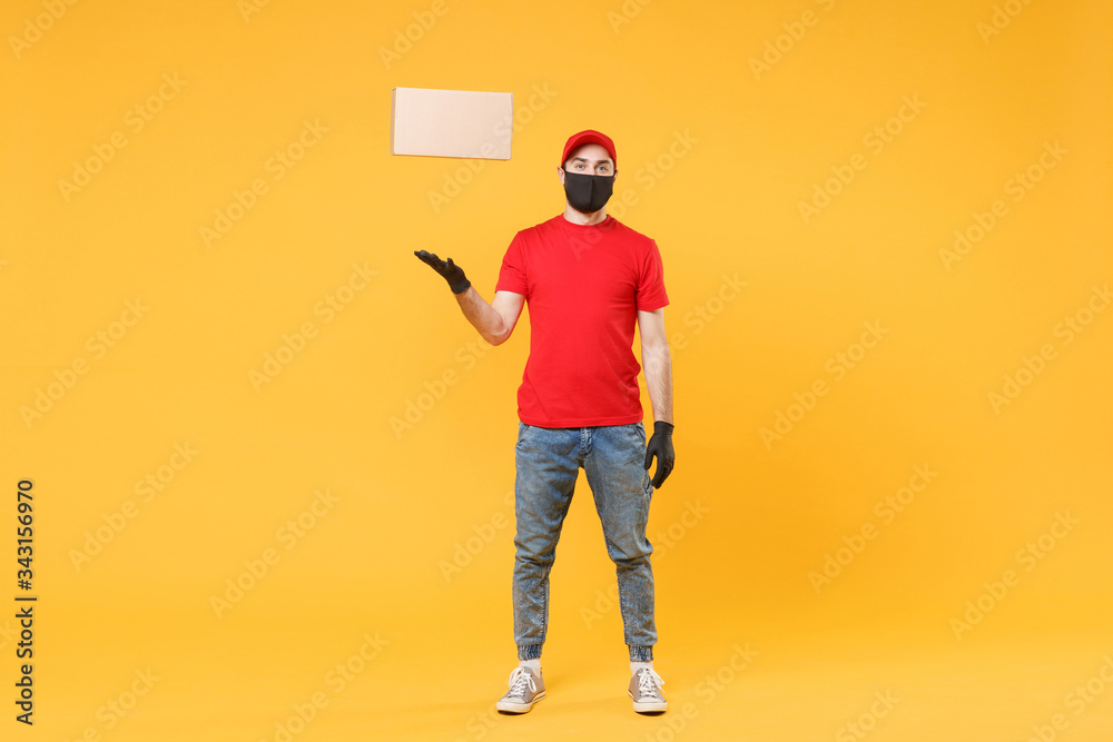 Delivery man employee in red cap blank t-shirt uniform face mask glove hold empty cardboard box isolated on yellow background studio Service quarantine pandemic coronavirus flu virus 2019-ncov concept