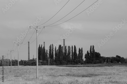 Concrete poles in line and in background multiple coal fossil fuel power plant