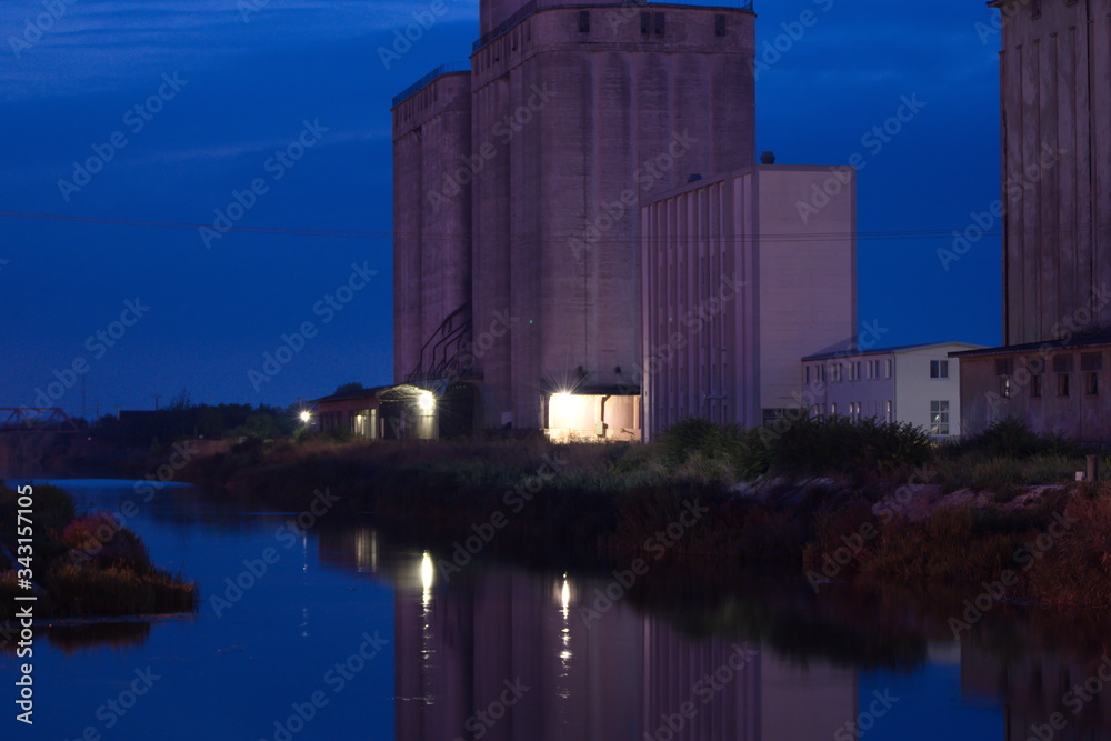 A high concrete building near the river at night