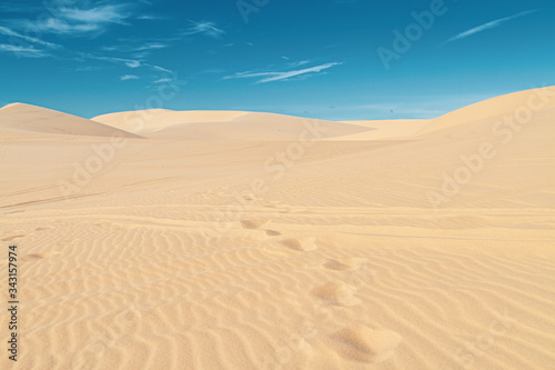 Footprints in the sand in the desert, no people, blue sky.