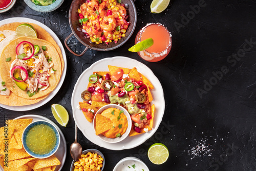 Mexican food, a flat lay on a dark background with copy space. Nachos, tortillas, Paloma cocktails, shot from above