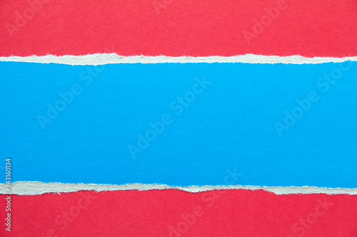 Blue torn piece of cardboard on red paper texture background. Copy space for text message.