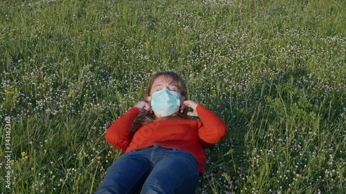 Girl takes off the medical face mask from her face in a field of flowers