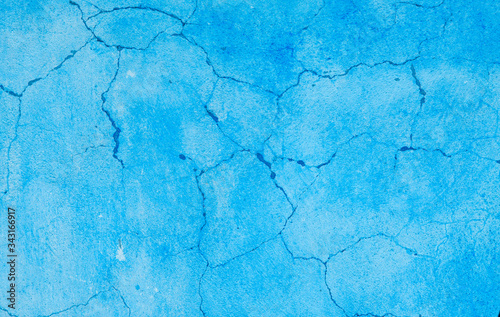 Blue bright background. Wall covered with old cracked stucco, tinted in turquoise color. Bright neon backdrop. Modern urban industrial concept. Copy space. Selective focus image.