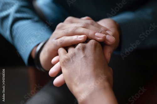 Close up of young multiethnic couple hold hands talking sharing secrets showing love and care, multiracial husband and wife have tender close moment together, demonstrate support and understanding