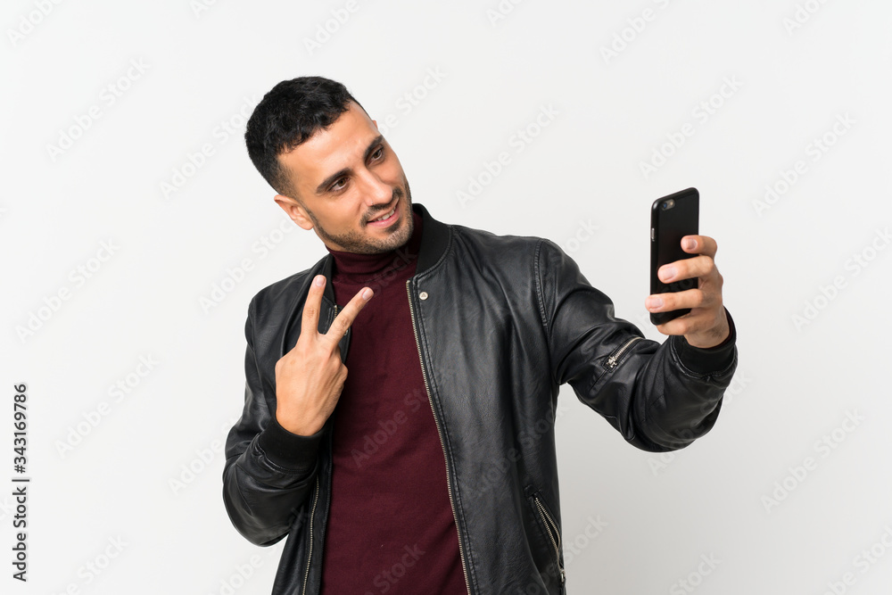 Young man over isolated white background taking a selfie with the mobile Young man over isolated white background taking a selfie with the mobile