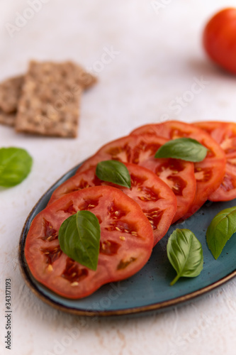 sliced tomatoes and basil on blue plate  