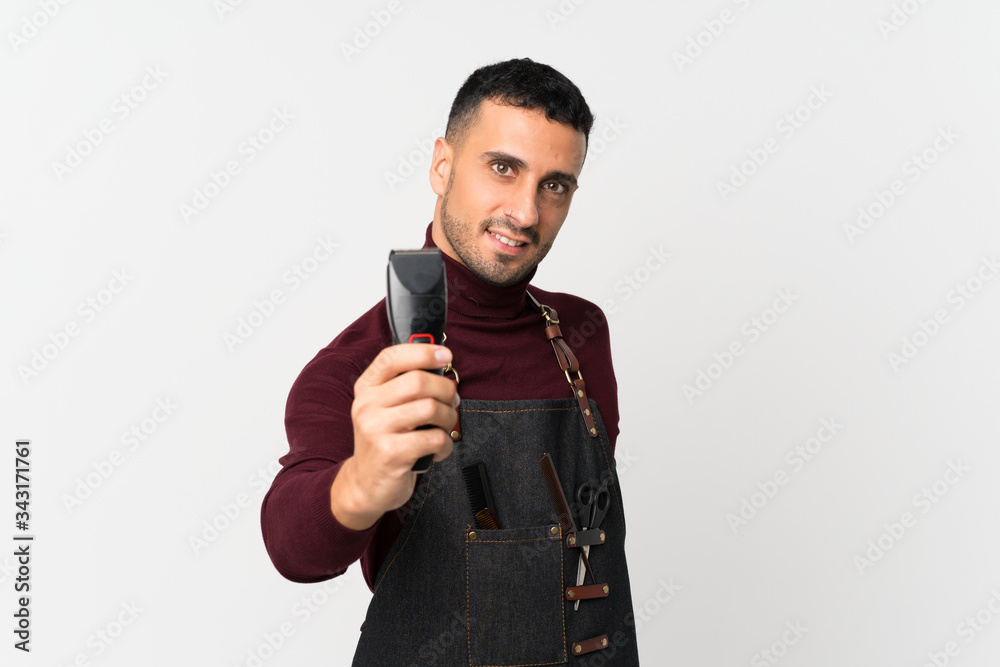 Young man over isolated white background with hairdresser or barber dress and holding hair cutting machine Young man over isolated white background with hairdresser or barber dress and holding hair cutting machine