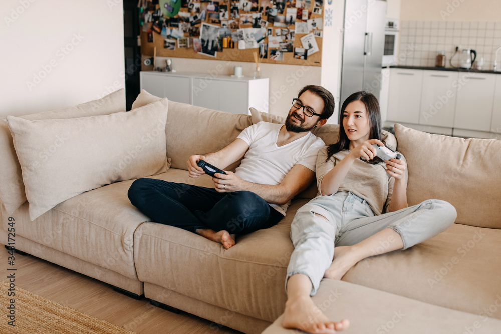 Young couple of man and woman playing video game on a console, sitting on couch in living room. Young couple of man and woman playing video game on a console, sitting on couch in living room.