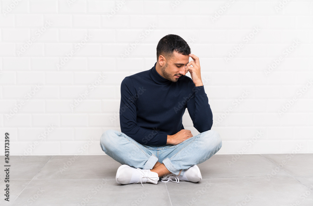 Young handsome man sitting on the floor laughing Young handsome man sitting on the floor laughing