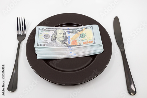 Plate full hundreds of dollar bills with fork and knife. Concept of prosperity and abundance. Full plate concept. Copy space