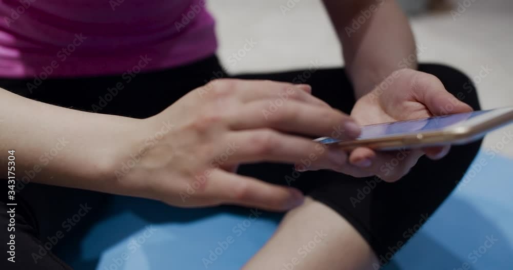 Beautiful healthy fit beautiful young woman in headphones holding smartphone in hands. Attractive sporty woman listening to the music while doing home workout. Beautiful healthy fit beautiful young woman in headphones holding smartphone in hands. Attractive sporty woman listening to the music while doing home workout.