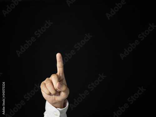 The hands of the businessman are pointing to touch something Is an object for graphic lines, able to add anything. With a black background, business, or financial concept.