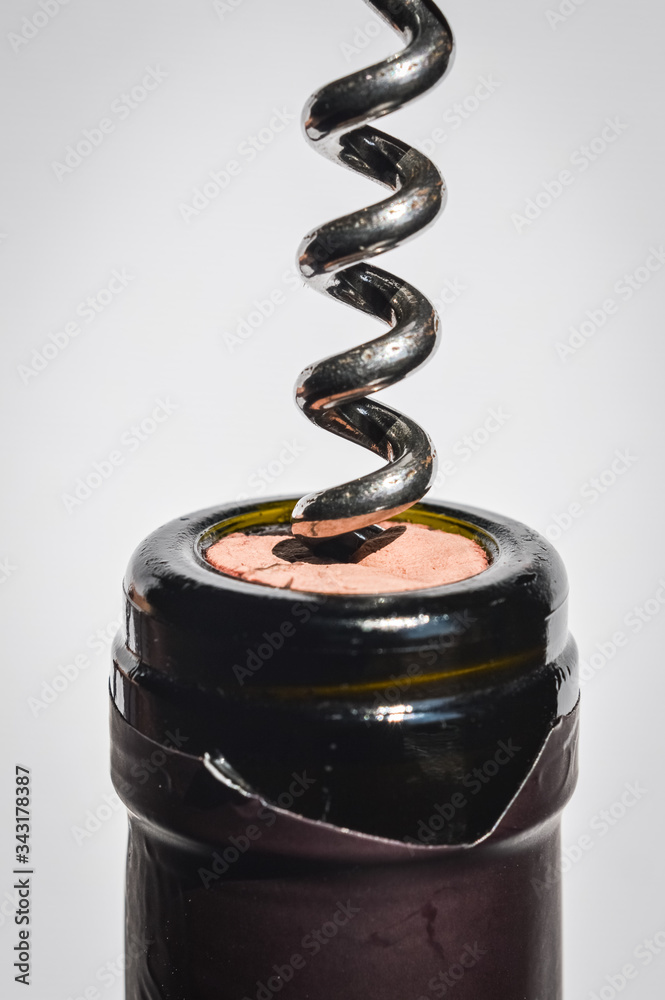 Bottle of wine and corkscrew close up, spiral is entering the cork, opening the bottle. Selective focus. Bottle of wine and corkscrew close up, spiral is entering the cork, opening the bottle. Selective focus.