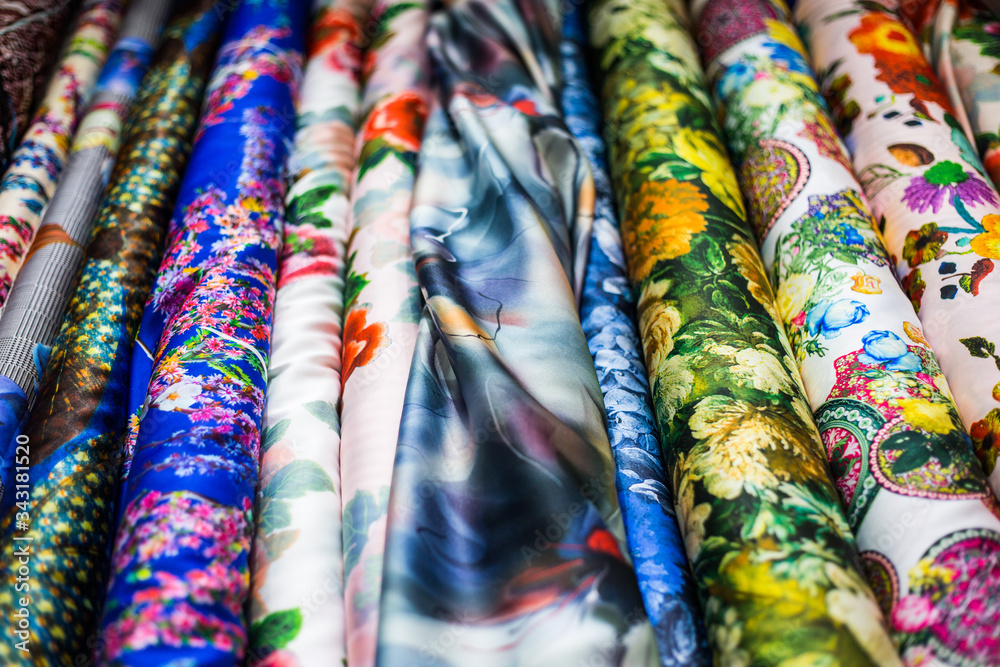 A row of colorful fabrics featuring a variation of flower designs on display in a sewing shop A row of colorful fabrics featuring a variation of flower designs on display in a sewing shop