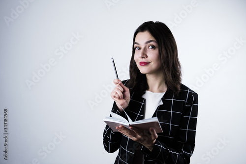 Cute girl with red lips and plaid jacket got an idea and writing it in her notepad with pencil