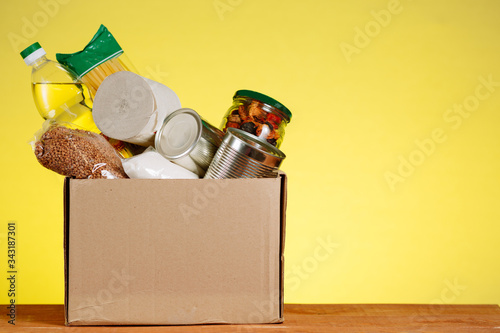 Food Donation concept. Donation Box With food For Donation On Yellow Backround. Assistance To The Elderly In The Context of The Coronavirus Pandemic