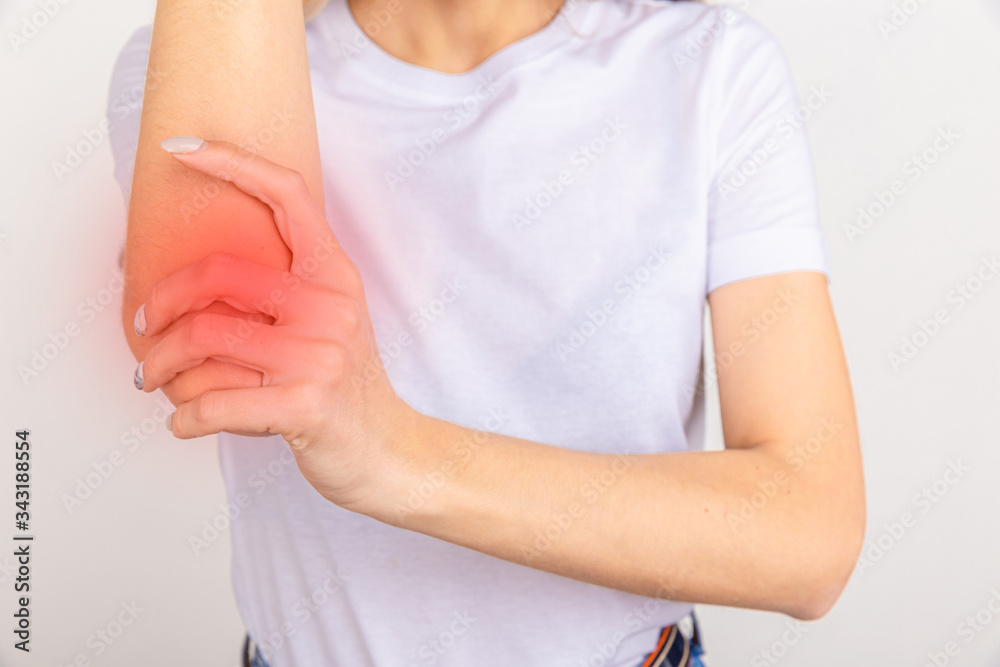 Young girl holding her elbow joint over white background. Pain and inflammation in the elbow. Young girl holding her elbow joint over white background. Pain and inflammation in the elbow.