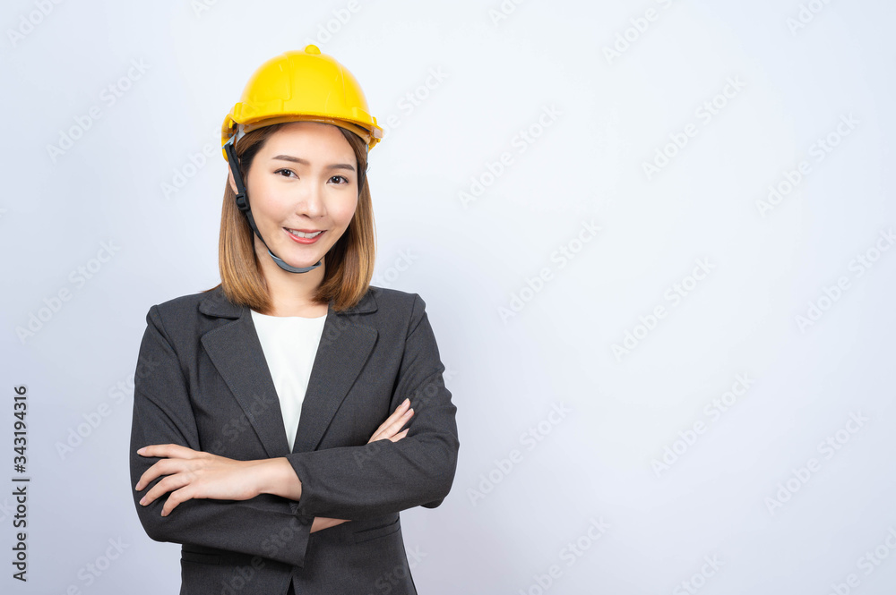 Portrait of Young Asian businesswoman wearing yellow safety-helmet in formal suit smiling looking at camera, shot in studio Portrait of Young Asian businesswoman wearing yellow safety-helmet in formal suit smiling looking at camera, shot in studio