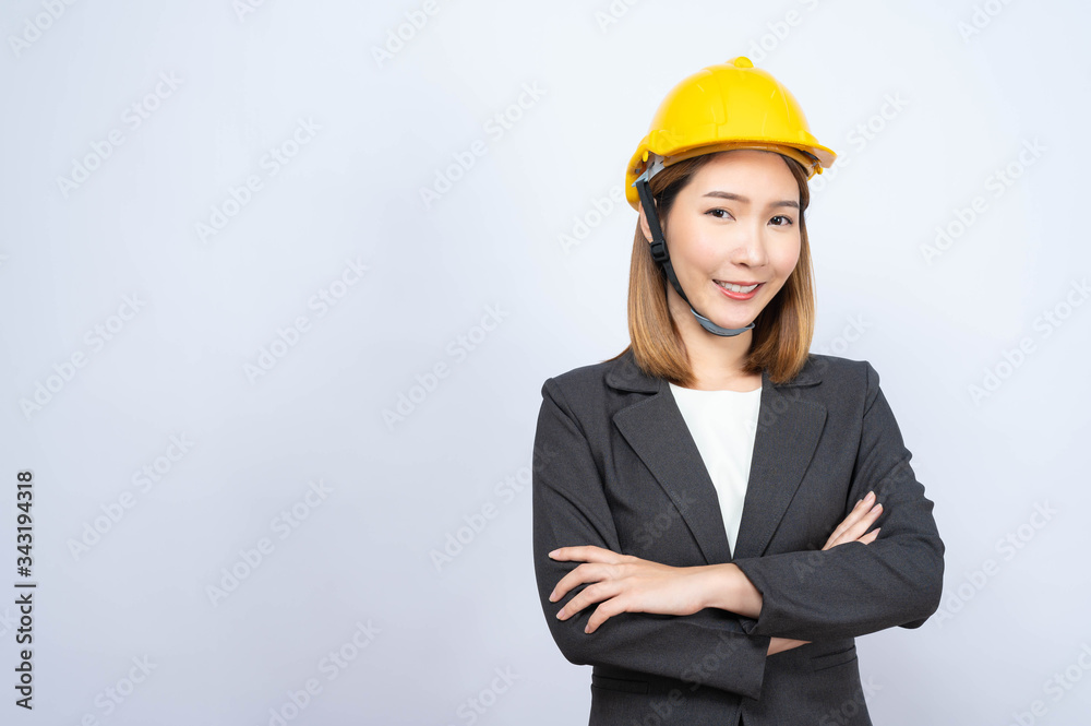Portrait of Young Asian businesswoman wearing yellow safety-helmet in formal suit smiling looking at camera, shot in studio Portrait of Young Asian businesswoman wearing yellow safety-helmet in formal suit smiling looking at camera, shot in studio