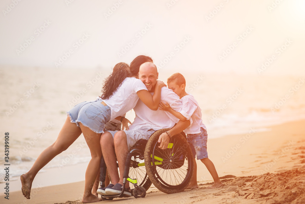 Disabled man in a wheelchair with his family on the beach.