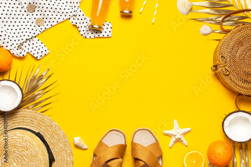 Summer background Beach accessories. Beach wicker straw rattan women's eco bag white dress hat sandals golden tropical leaf coconut orange juice shells starfish on yellow background. Flat lay top view
