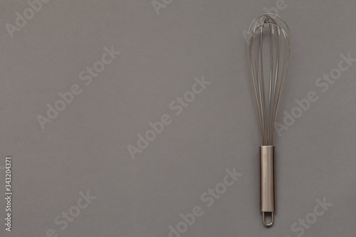 Metal whisk for whipping on a gray background.