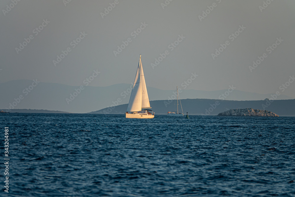 Sailing boat at sea. Yacht is sailing in the Adriatic Sea against the backdrop of forested islands, Croatia.