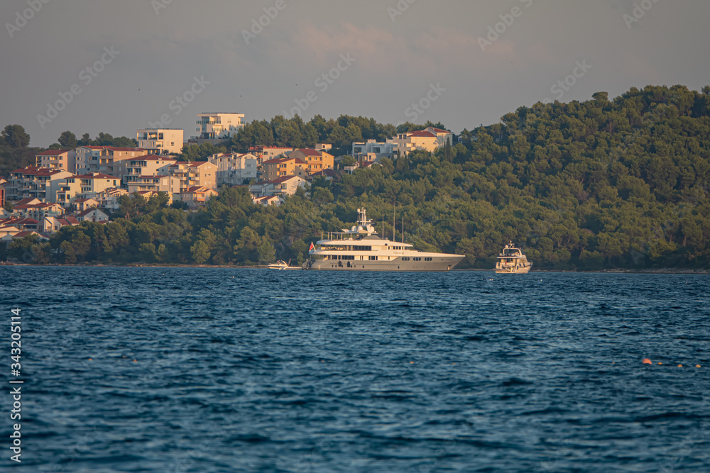 Yachts and boats sail along the island of Ciovo in the Adriatic Sea at sunset, Croatia.