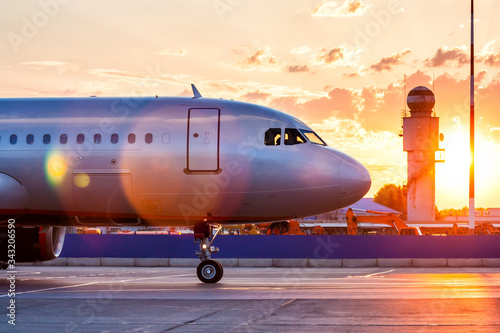 Close-up of the front of a passenger airplane. Aircraft taxiing on the apron of the airport in the rays of a picturesque sunrise