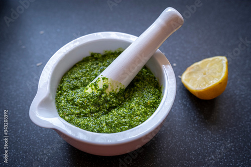 Making wild garlic pesto by grinding wild garlic leaves with olive oil, pine nuts, hazelnuts, lemon juice and olive oil in a mort and pestle