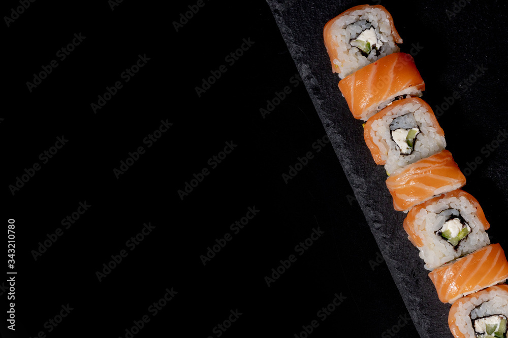 Philadelphia roll with salmon, cheese and cucumber on a black background. Sushi Philadelphia
