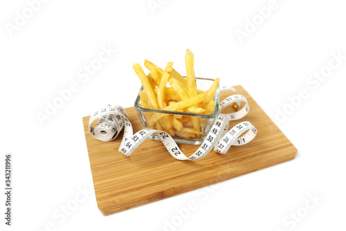 French fries in a glass plate. Bamboo board. White background. Isolated objects. Tape measure. Diet concept