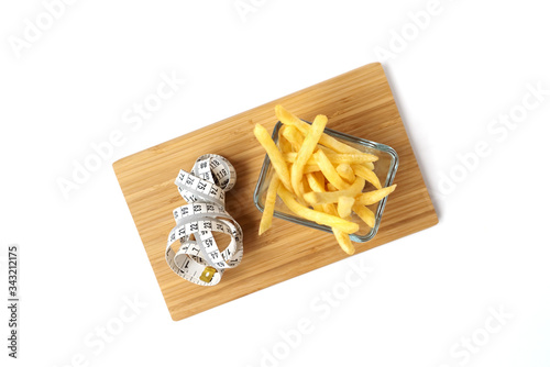 French fries in a glass plate. Bamboo board. White background. Isolated objects. Tape measure. Diet concept