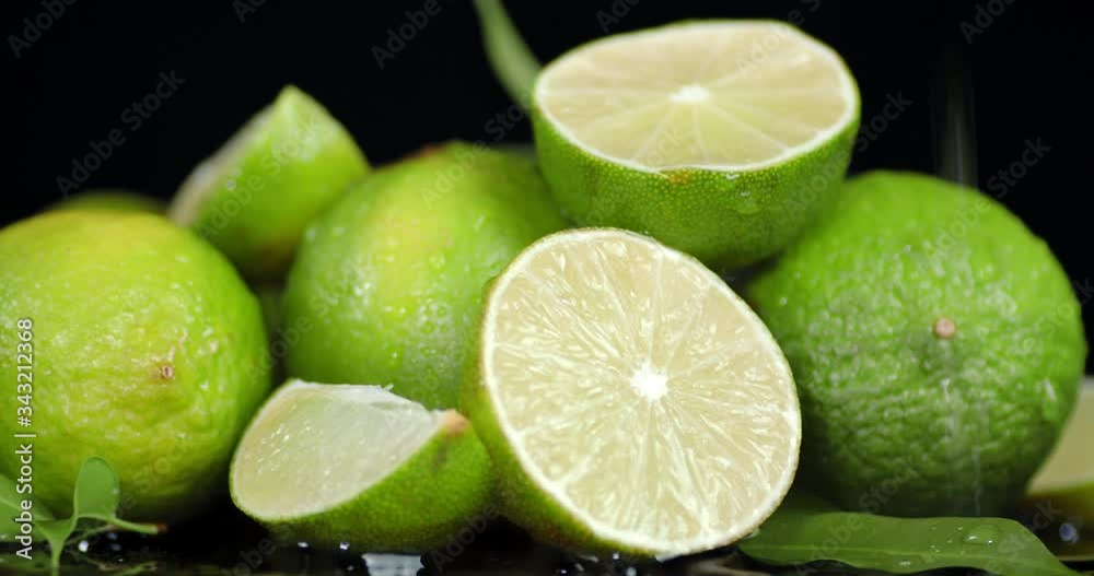 On juicy limes with leaves falling drops of water.
