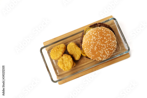 Cheeseburger, nuggets in the glass plate. Bamboo board. White background. Isolated objects.
